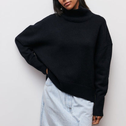 Frau in schwarzem Rollkragenpullover und hellblauem Jeansrock vor weißem Hintergrund.