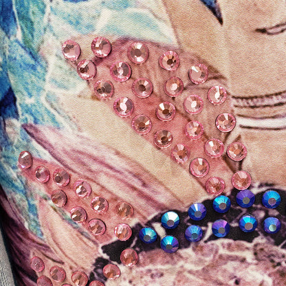 Nahaufnahme von rosa und blauen Strasssteinen auf bedrucktem Stoff, glitzerndes Design.