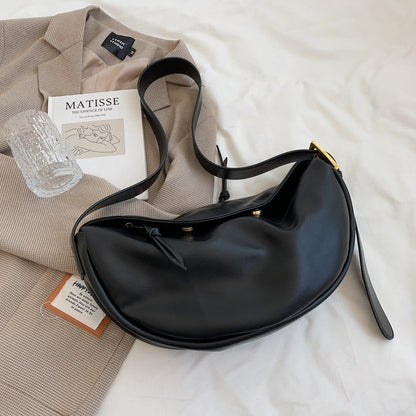 Schwarze Lederhandtasche auf beigem Blazer, modernes Design, elegantes Accessoire.