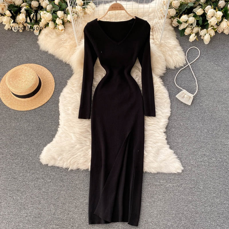 Schwarzes langärmeliges Strickkleid, figurbetont, auf Teppich mit Strohhut und Handtasche.