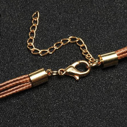 Braunes Lederarmband mit goldfarbenem Karabinerverschluss und Kettenverlängerung auf schwarzem Hintergrund.