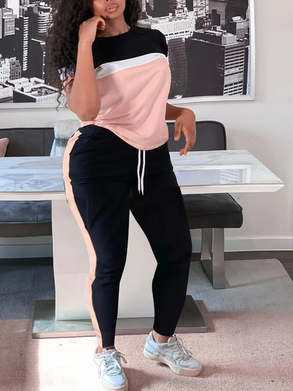 Frau in rosa-schwarzem Jogginganzug vor modernem Tisch, Stadtbild im Hintergrund.