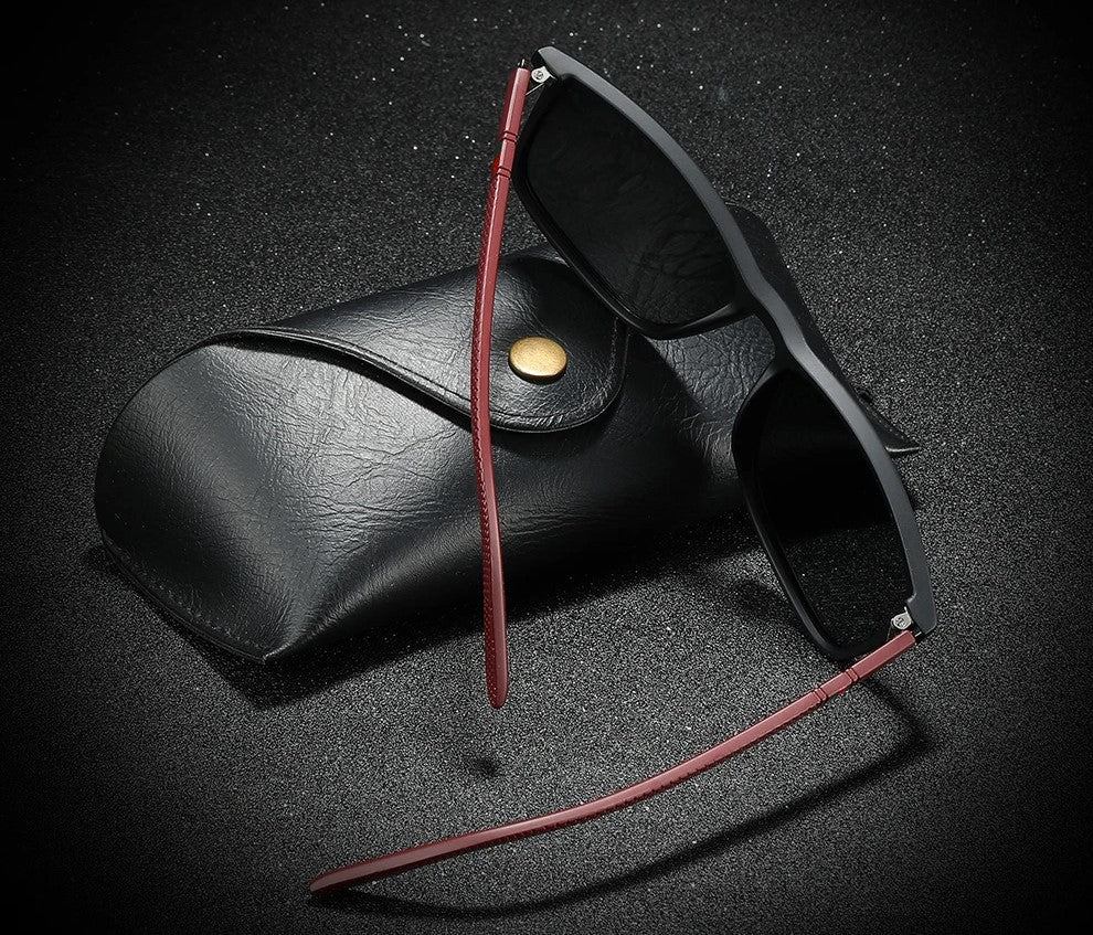 Schwarze Sonnenbrille mit rotem Bügel und Etui, modisches Accessoire, UV-Schutz.