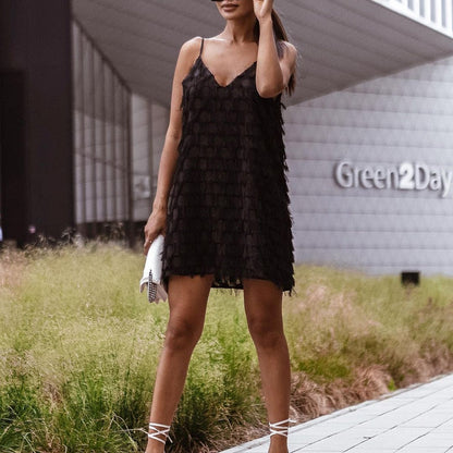 Frau in schwarzem Cocktailkleid mit Clutch vor modernem Gebäude, Sommermode, Abendkleidung.