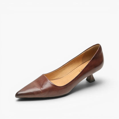 Mörkbrun slip on-sko med spetsig tå och låg klack, snett framifrån mot vit bakgrund 17