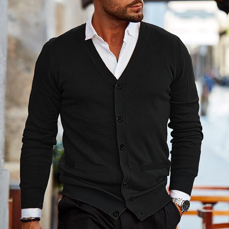 Mann in schwarzem Strick-Cardigan mit weißem Hemd, eleganter Herrenmode, urbaner Hintergrund.