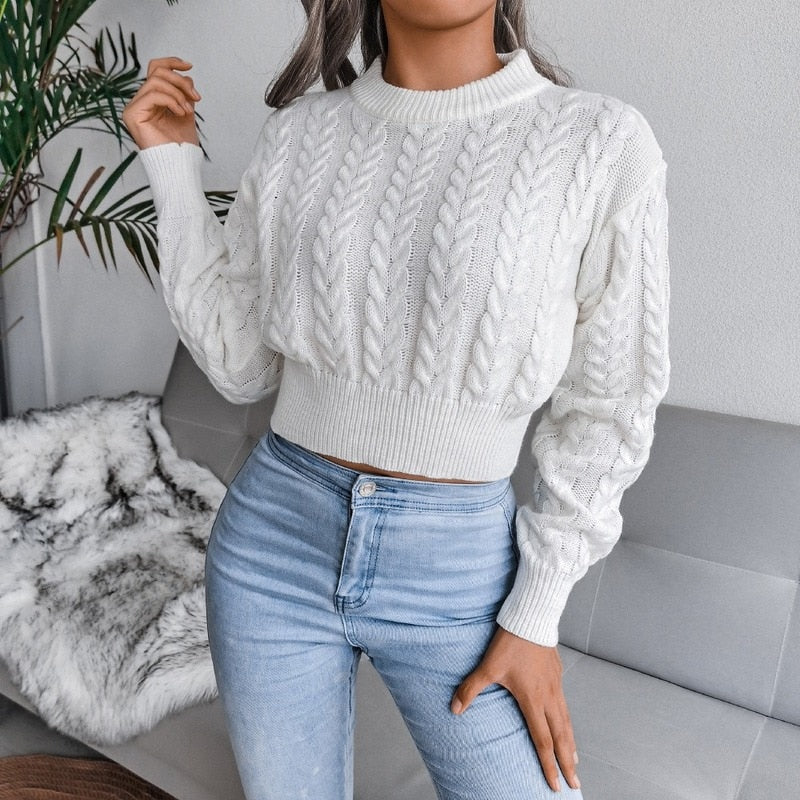 Frau in weißem Strickpullover, Zopfmuster, hoch taillierte blaue Jeans, modisch, gemütlich.