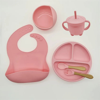 Rosa Silikon-Babygeschirr-Set mit Lätzchen, Teller, Schüssel, Becher und Besteck.