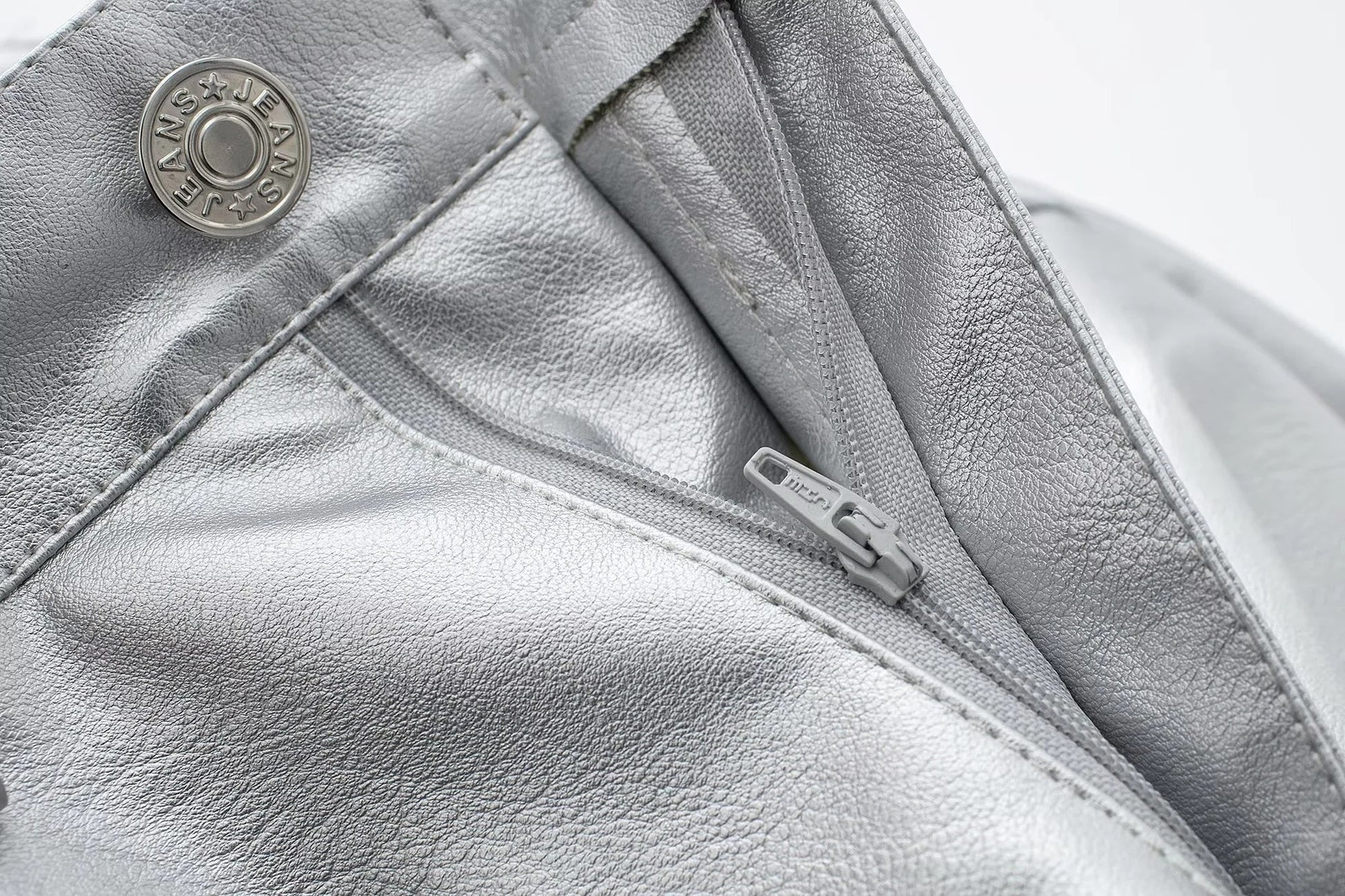 Silberne Lederjacke mit Reißverschluss, modisch, hochwertig, Jeans-Logo, Nahaufnahme.