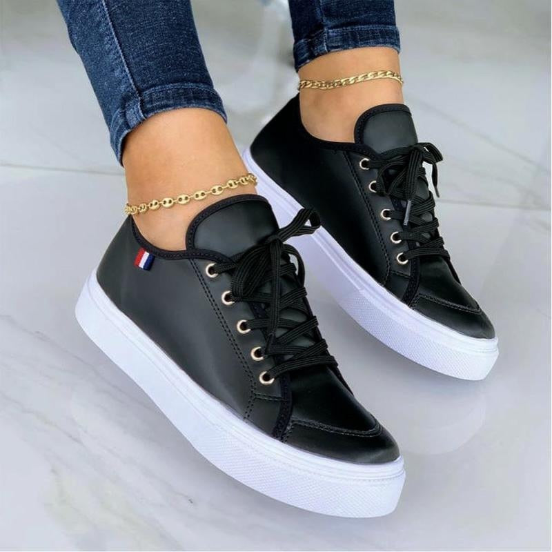 Schwarze Damen-Sneaker mit weißer Sohle, Lederoptik, goldene Knöchelketten, Jeans.