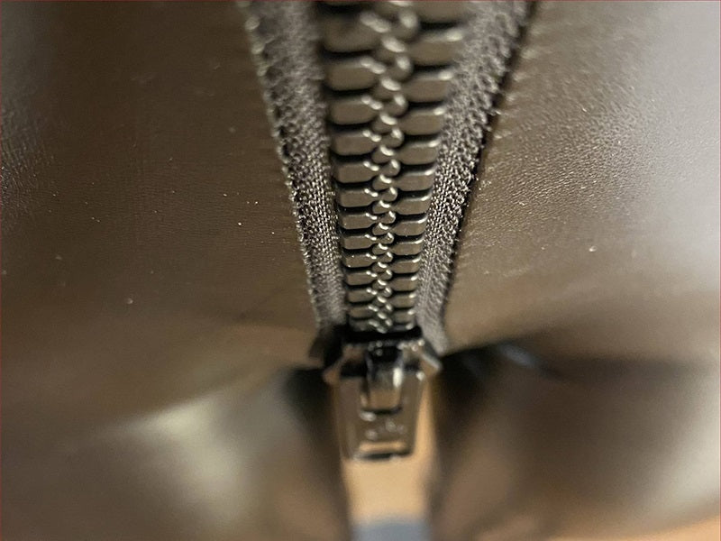 Schwarzer Reißverschluss aus Metall auf Lederjacke, Nahaufnahme, Modeaccessoire.