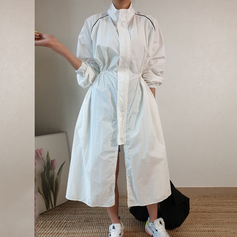 Frau in weißem Hemdkleid, knielang, mit Sneakers, moderne Mode, minimalistischer Stil.