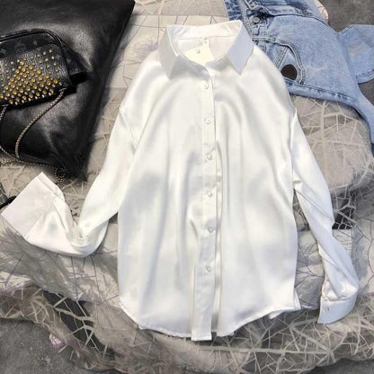 Weiße Seidenbluse Damen, langärmlig, elegant, auf Bett mit Jeans und Lederjacke.
