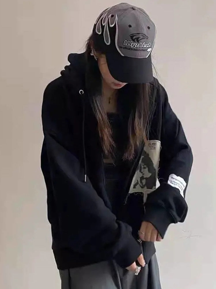 Frau in schwarzem Hoodie und Baseballkappe mit Flammen-Design, lässige Streetwear-Mode.