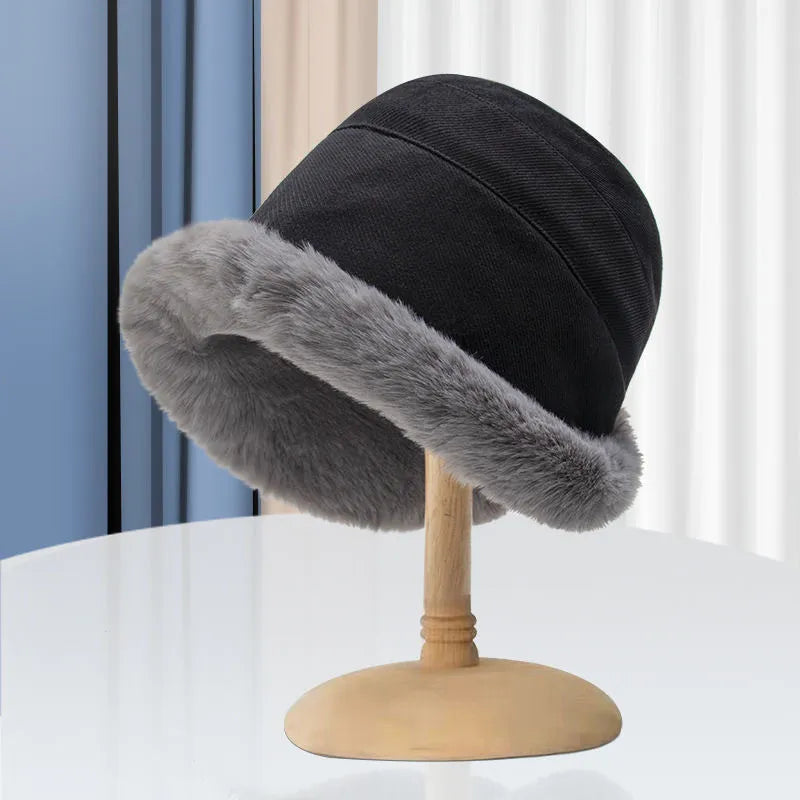 Schwarzer Eimerhut mit grauem Kunstfellrand auf Holzständer, modisch, warm, Winteraccessoire.