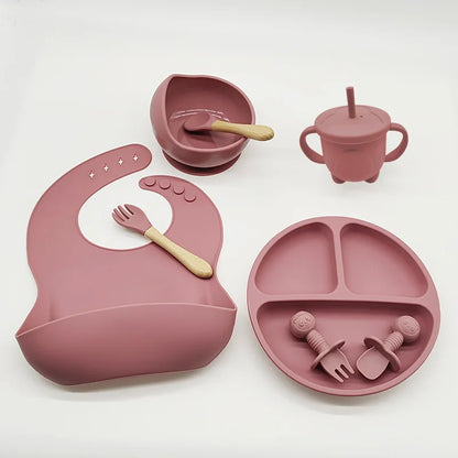 Rosa Silikon-Babygeschirr-Set mit Lätzchen, Teller, Schüssel, Becher und Besteck.
