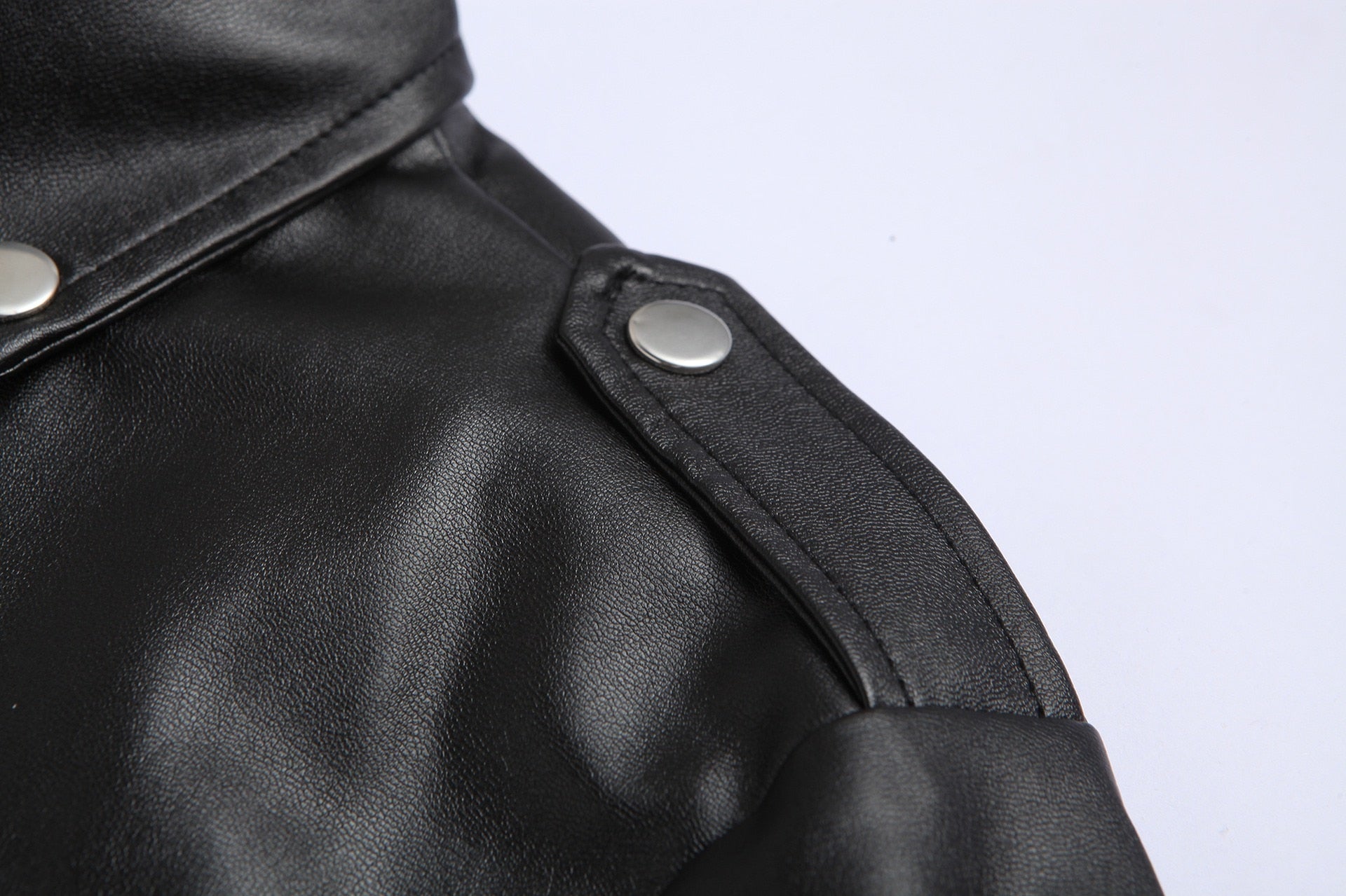 Schwarze Lederjacke mit silbernen Knöpfen, Nahaufnahme, modisches Design, hochwertige Materialien.
