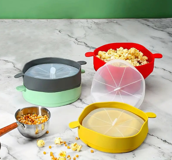 Bunte Silikon-Popcornschalen mit Deckel auf Marmortisch, ideal für Mikrowelle.