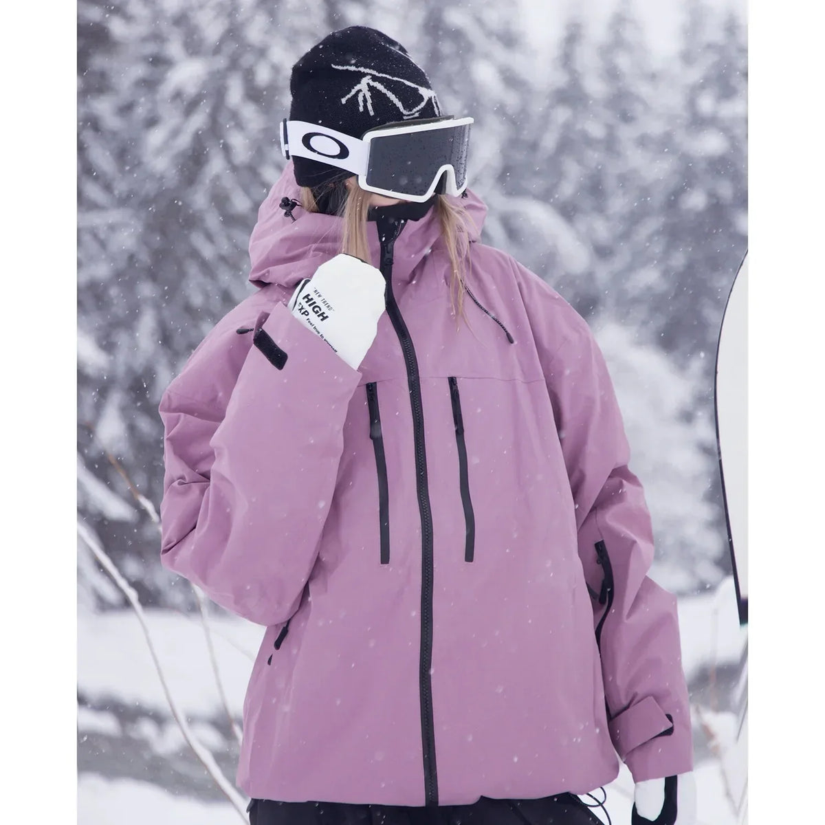 Närbild på modell i rosa jacka från sidan, med bröstfickor med dragkedja, uppfälld krage och hand mot hakan. 4