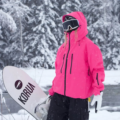 Modell i knallrosa jacka med uppdragen huva håller ett snowboard under armen i snöig skog. 5