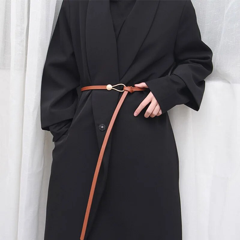 Brauner, verstellbarer Ledergürtel an schwarzem Mantel, modisches Accessoire für Damen.