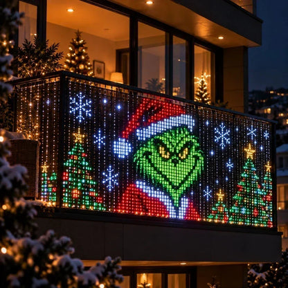 Ljusgardin på ett balkongräcke visar en grön figur med tomteluva, omgiven av granar och snöflingor 9
