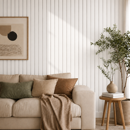 Vardagsrum med beige soffa framför vit ribbvägg, inramad tavla och växt i hörnet 10