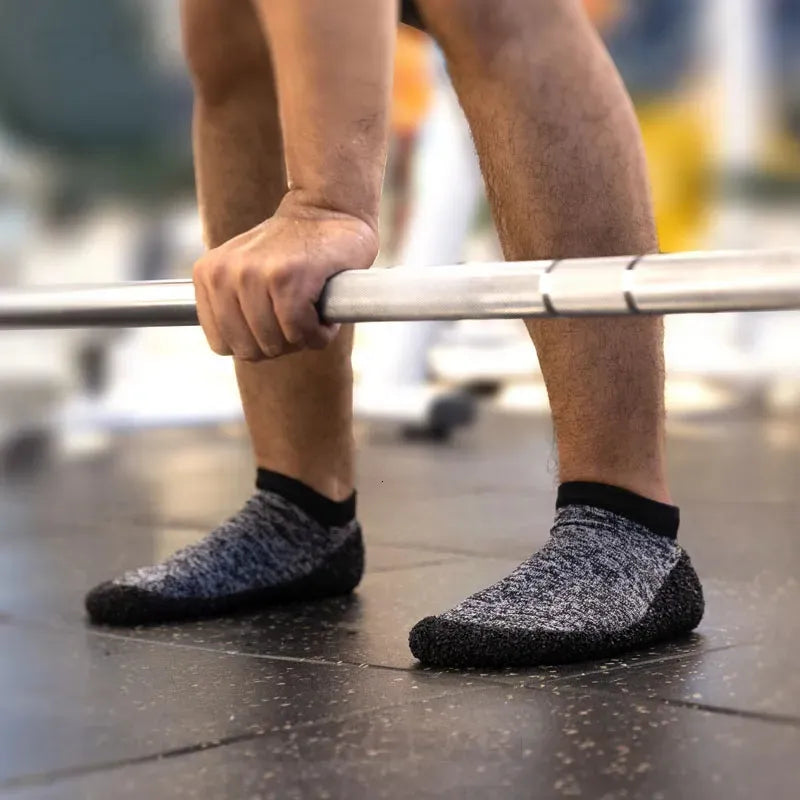 Mann hebt Hantel in grauen rutschfesten Fitnesssocken, ideal für Krafttraining im Fitnessstudio.