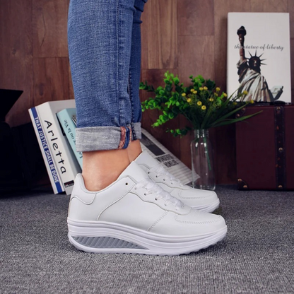 Weiße Damen-Sneaker, orthopädisch, bequem, aus Leder, getragen mit blauen Jeans.