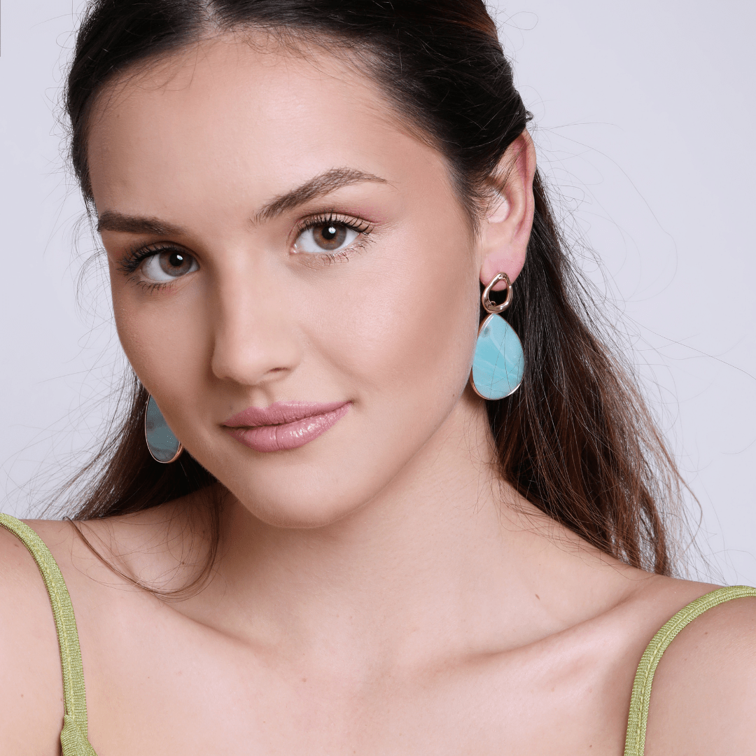 Frau mit türkisfarbenen Ohrringen, elegantes Design, modisches Accessoire, Nahaufnahme.