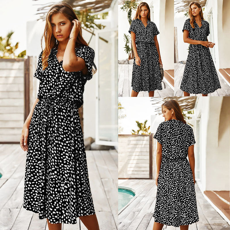 Frau in schwarzem Sommerkleid mit weißen Punkten, knielang, kurzärmelig, draußen.
