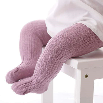 Baby in rosa Strumpfhose aus Baumwolle auf weißem Stuhl, gemütliche Kinderbekleidung.