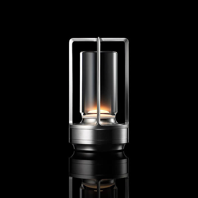 Lampa med silverfärgad ram och bas, tänd mot svart bakgrund med reflektion, sedd framifrån. 10