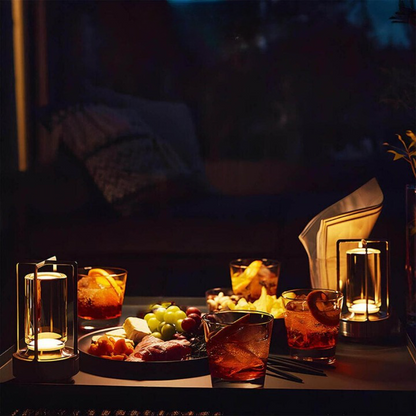 Två tända lampor står på ett bord med drinkar, frukt och snacks i kvällsmörker. 6