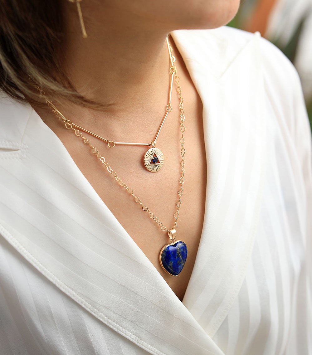 Frau mit goldener Halskette, Lapis-Lazuli-Herzanhänger, modisches Schmuckdesign.