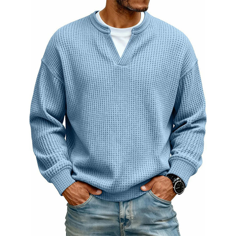 Ljusblå våffelstickad tröja med lång ärm på modell, vit t-shirt under, händerna i jeansfickorna 4
