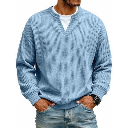 Ljusblå våffelstickad tröja med lång ärm på modell, vit t-shirt under, händerna i jeansfickorna 4