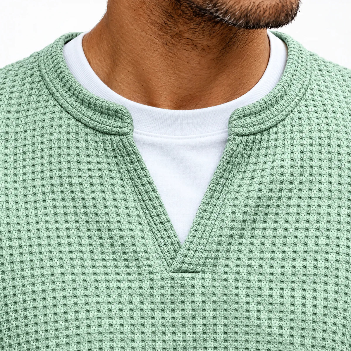 Närbild på tröjans urringning i mintgrön våffelstickning med V-skåra och vit t-shirt som tittar fram 3