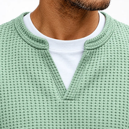 Närbild på tröjans urringning i mintgrön våffelstickning med V-skåra och vit t-shirt som tittar fram 3