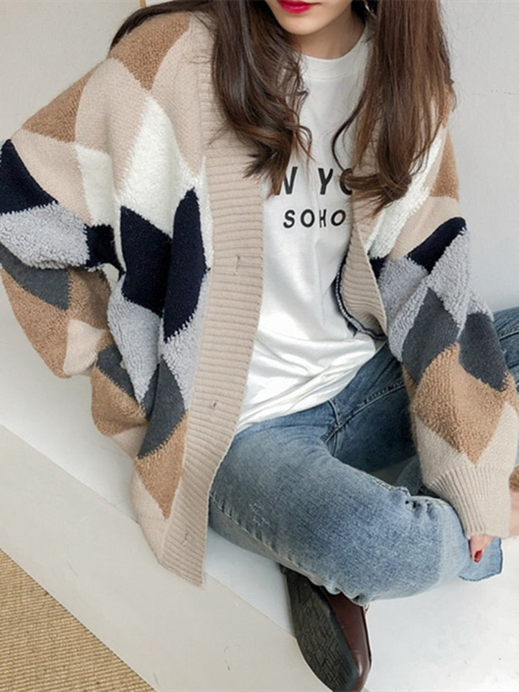 Frau trägt beige-graue Strickjacke mit geometrischem Muster, lässig über weißem T-Shirt.