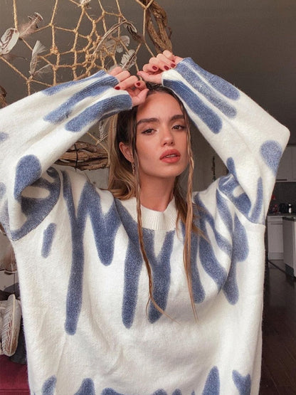 Frau in weiß-blauem Oversize-Pullover mit abstraktem Muster, gemütliche Wintermode.