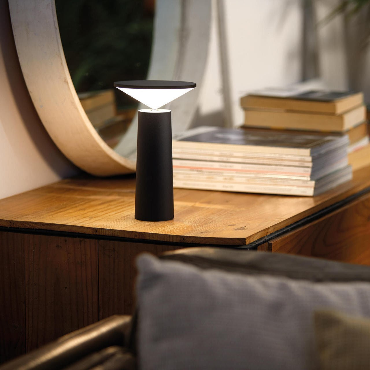Schwarze LED-Tischlampe auf Holzoberfläche vor Spiegel, modernes Design.