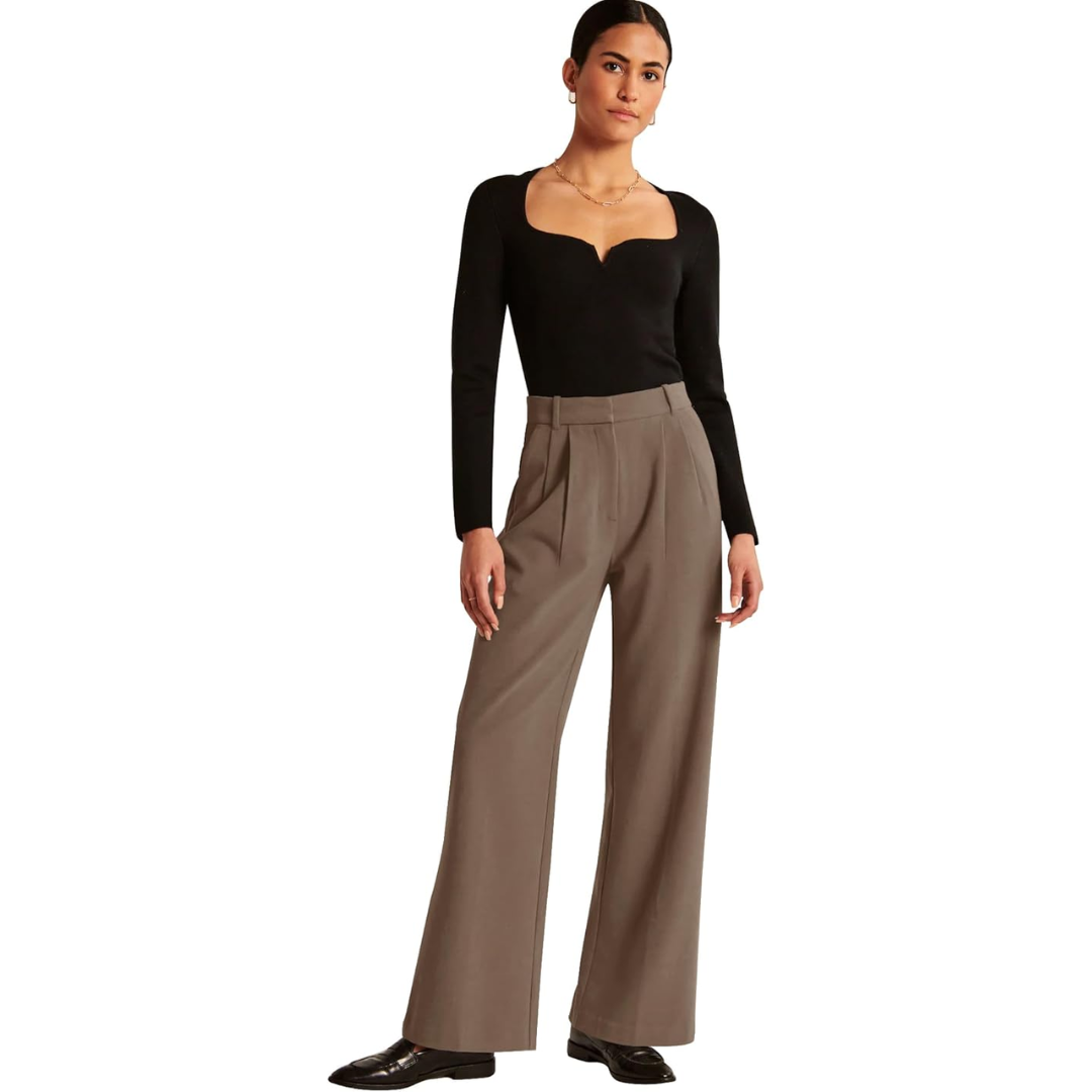 Frau in schwarzem Oberteil und brauner Hose, elegante Mode, Herbstkollektion, Studioaufnahme.