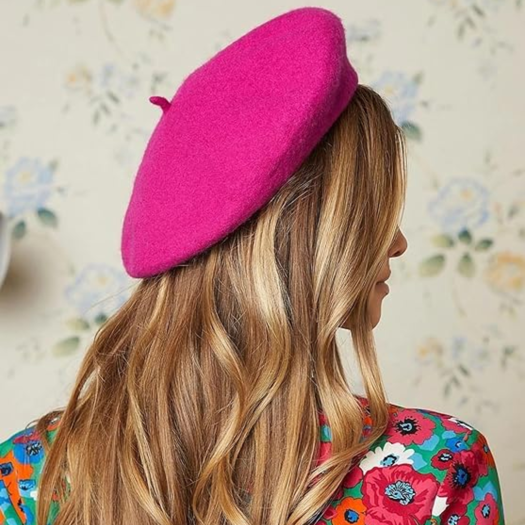 Frau mit pinkem Woll-Baskenmütze, blondes Haar, florales Kleid, modisches Accessoire.
