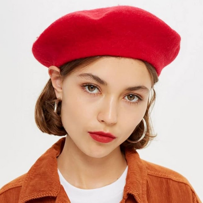 Frau mit rotem Woll-Baskenmütze, brauner Jacke, silbernen Ohrringen, modisches Accessoire.