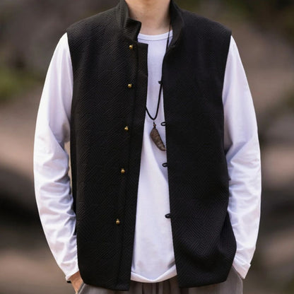 Schwarze Herrenweste mit goldenen Knöpfen, über weißem Langarmshirt, lässiger Stil.