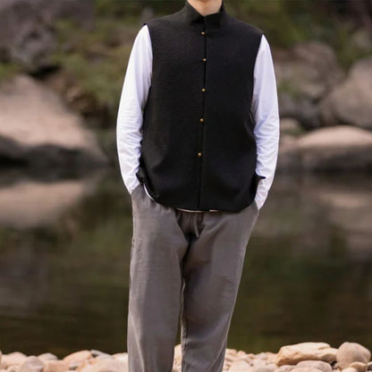 Mann in schwarzer Weste und grauer Hose vor Flusslandschaft, Outdoor-Mode, Freizeitkleidung.