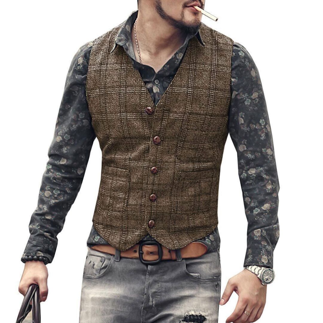 Mann mit brauner Tweed-Weste, gemustertem Hemd, Jeans und Uhr, lässiger Stil.