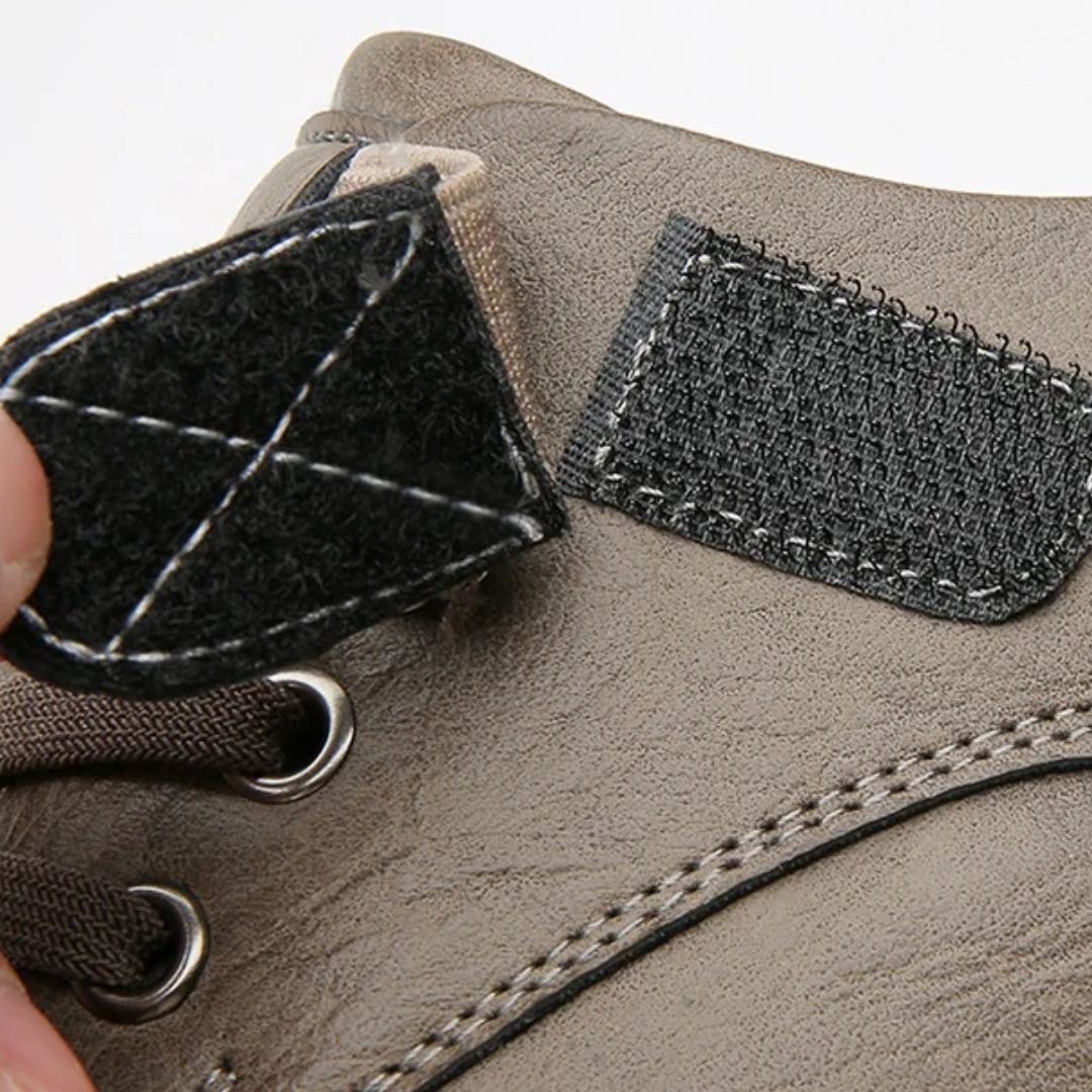 Grauer Wanderschuh mit Klettverschluss, robustes Leder, Outdoor-Aktivitäten, langlebig.