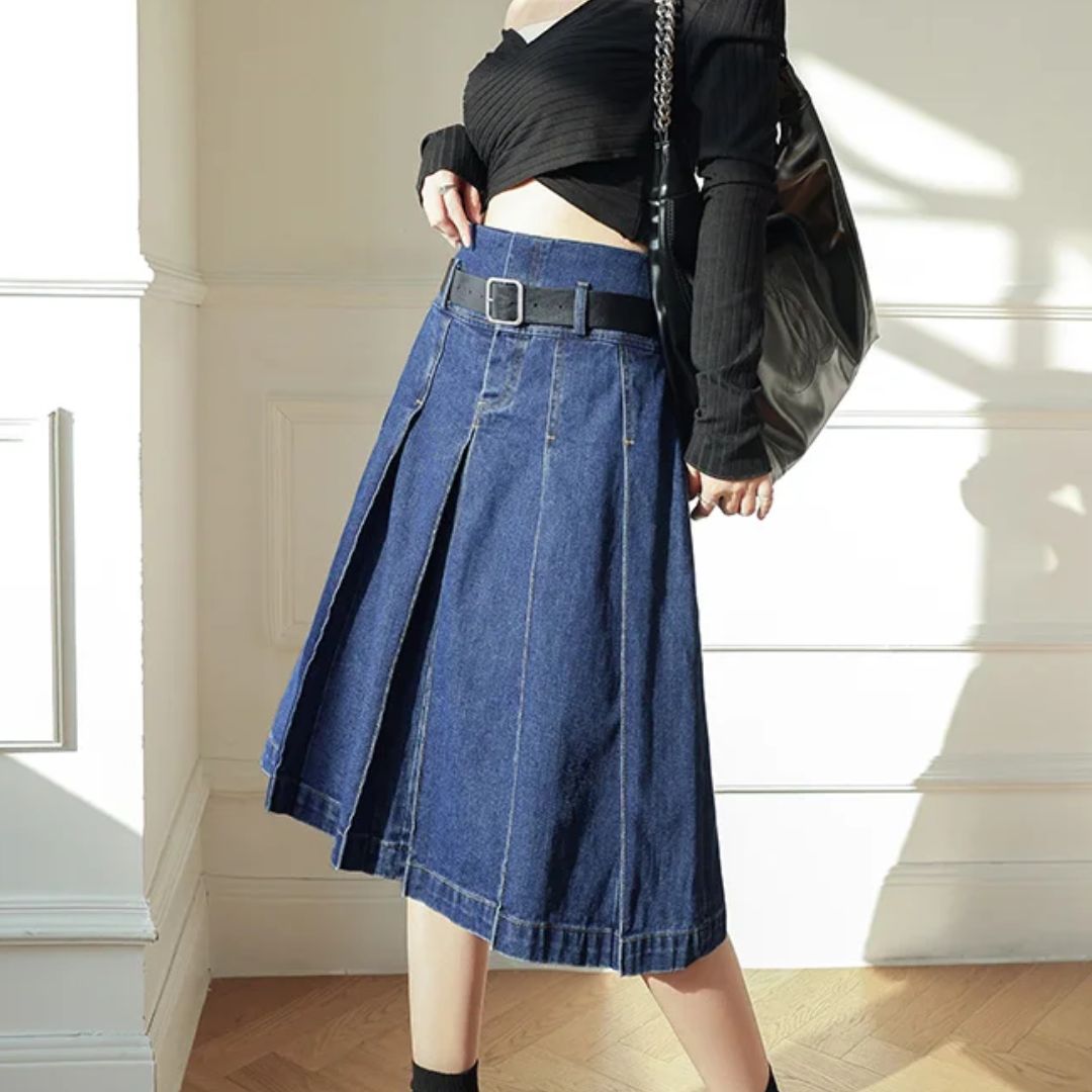 Frau in blauem Jeansrock mit Gürtel, schwarzem Oberteil und Tasche, modisch, elegant.